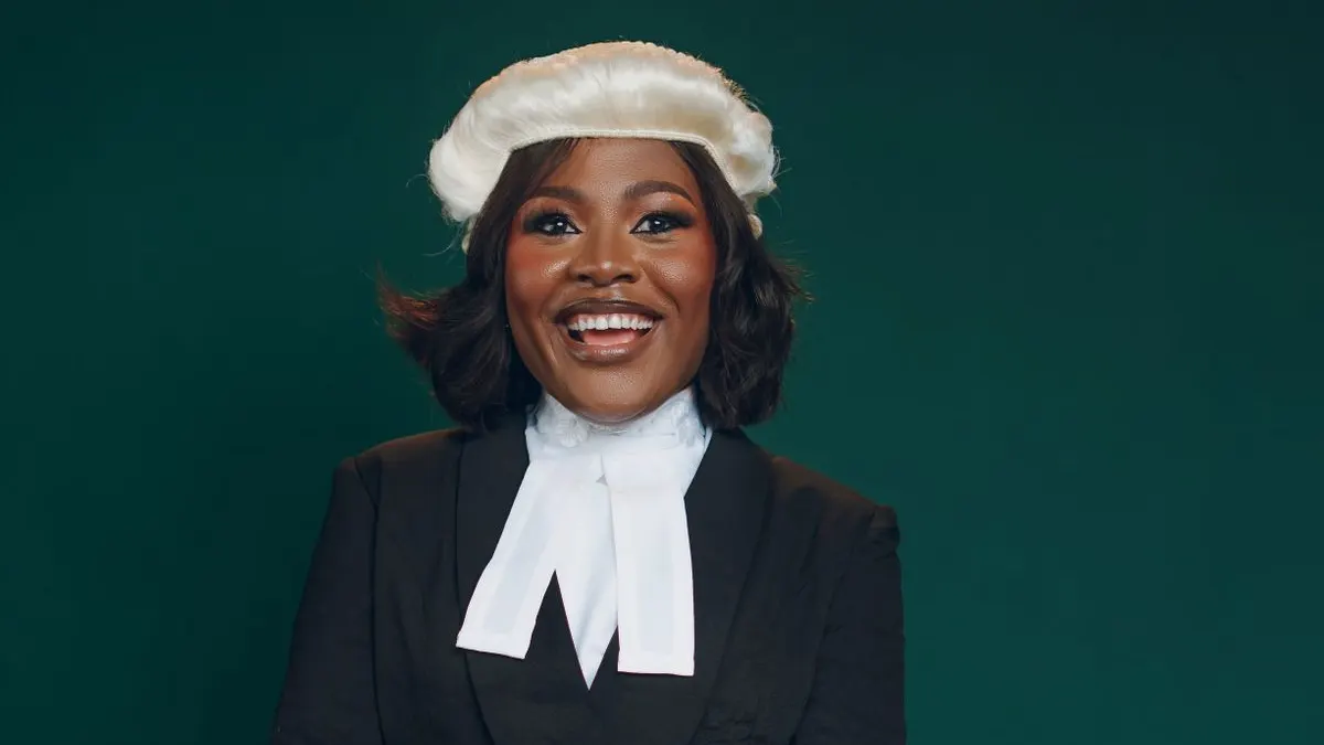 Smiling advocate in a court wig, bands and black jacket