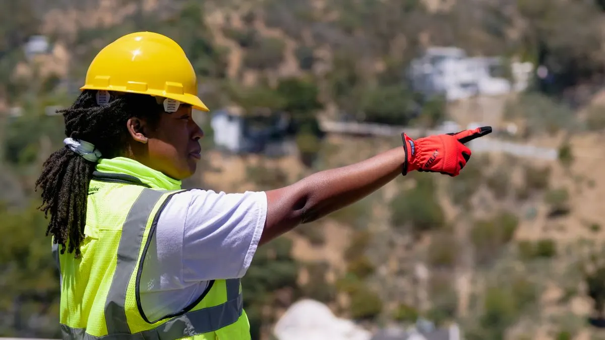 Safety officer in a hard hat and high-visibility vest directing work on a site