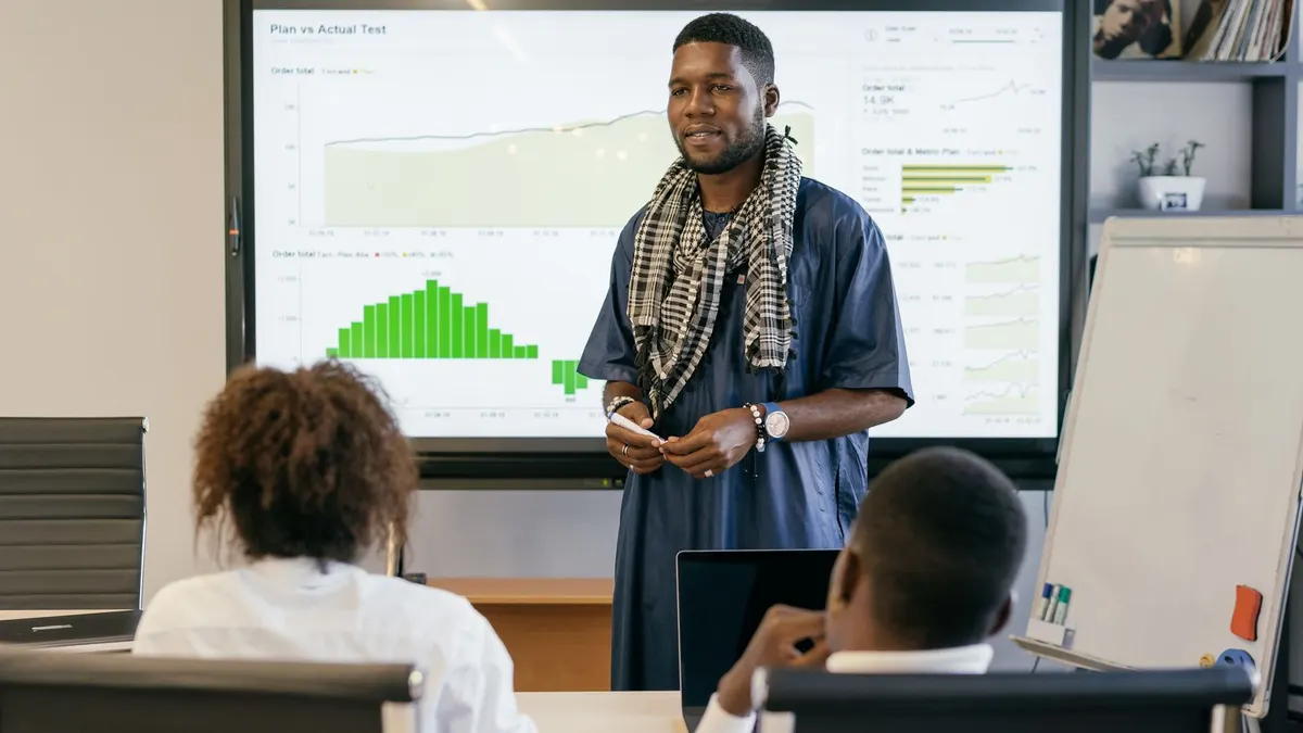 Office team listening as a colleague presents a chart on a large screen