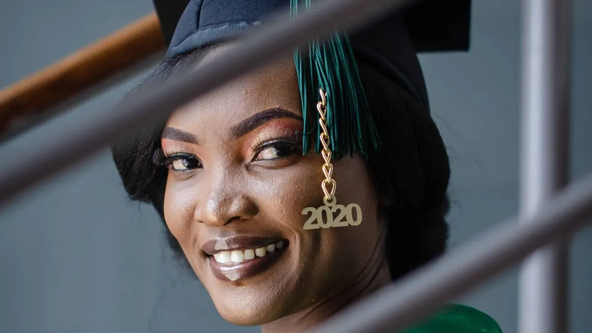 Smiling Kenyan university graduate in graduation gown ready to start her career