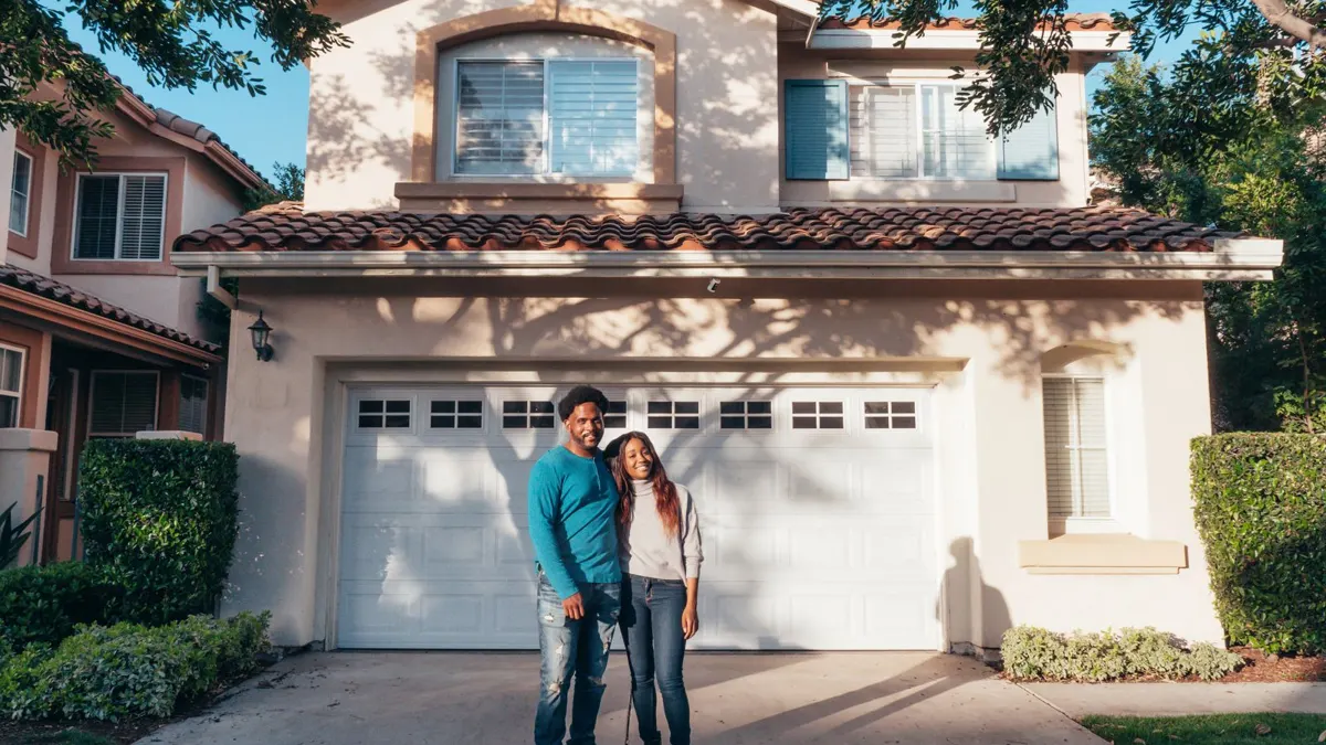 Young Black couple standing together in front of a house