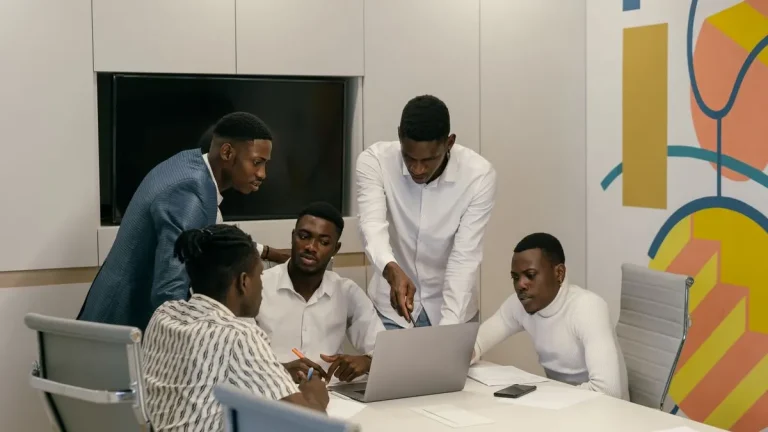 Young Kenyan interns working on a project together around a laptop in an office