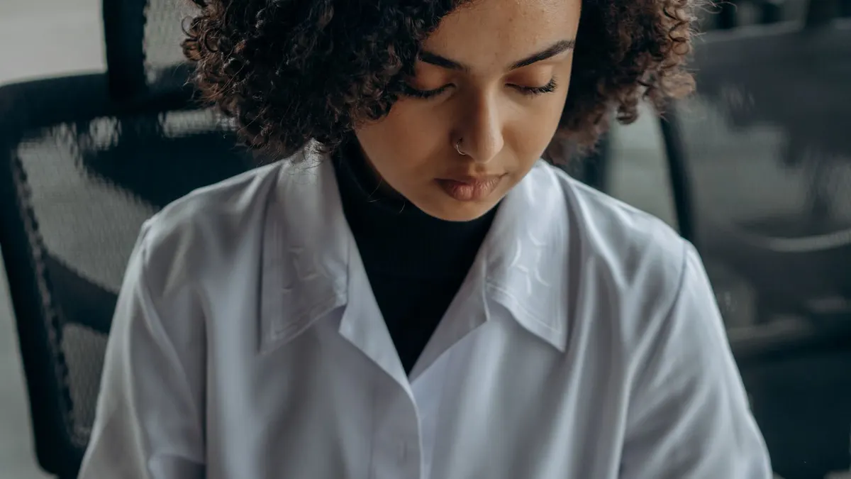 Young Black woman in a white shirt working through tax documents at her desk